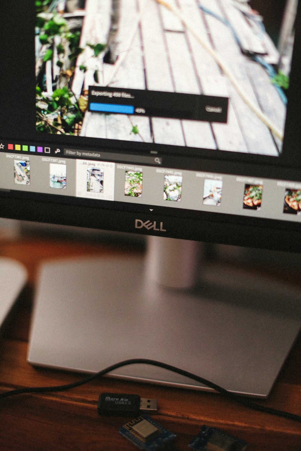 A computer monitor displays file export progress on a wooden desk.