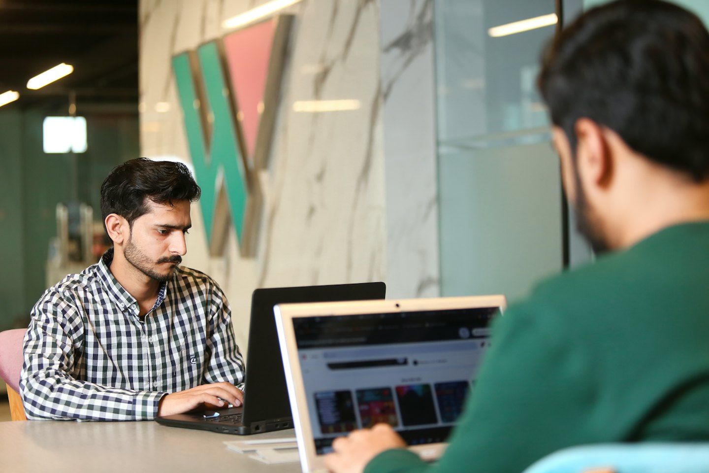 Man typing on his laptop in a modern office.